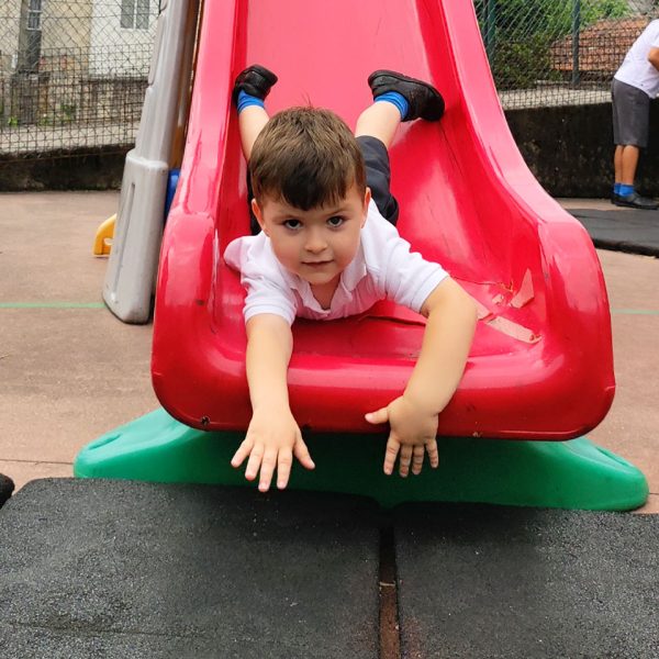 niño con el uniforme del colegio Atalaya Cantabria bajando por un tobogán en el recreo